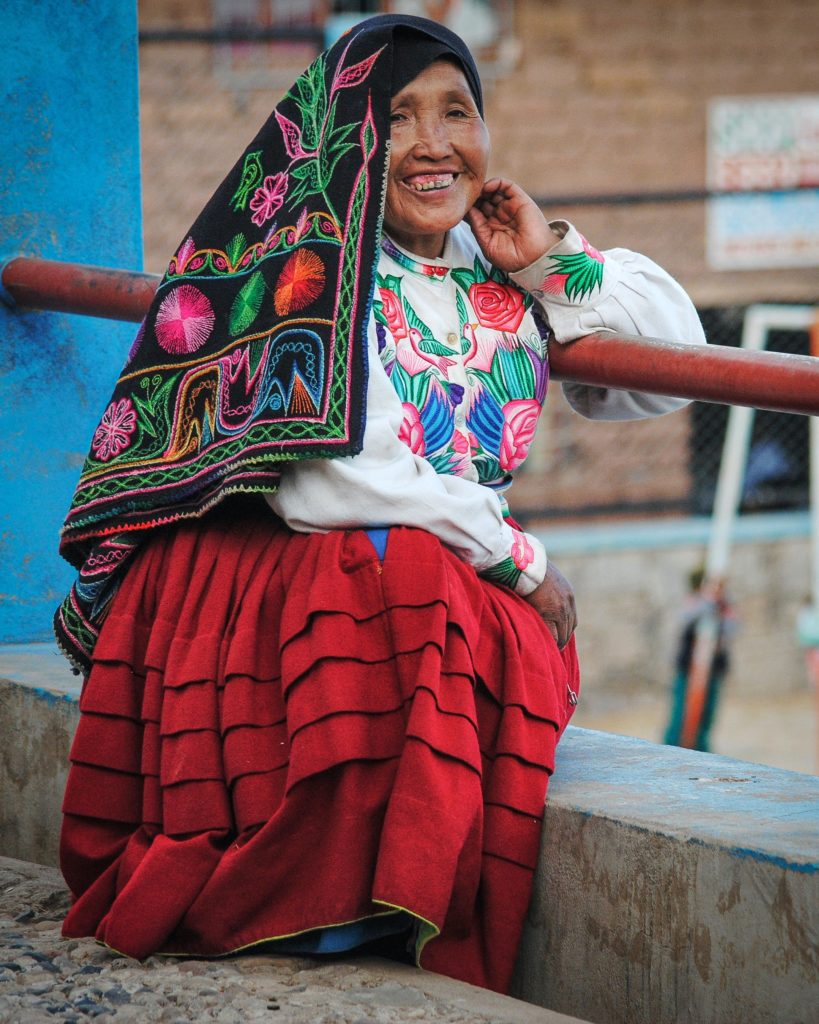 Mujer con traje tradicional, blusa bordada, chal bordado y falda color rojo. Imagen utilizada para el post "La conversación entre culturas" de Carlos Mendoza Sepúlveda.
